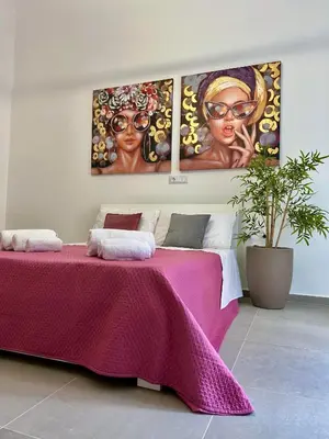a bedroom with a pink bed with three paintings on the wall at Leonetti Due in Carini