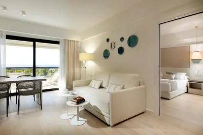 a living room with a white couch and a bedroom at Grand Palladium Sicilia Resort & Spa in Campofelice di Roccella