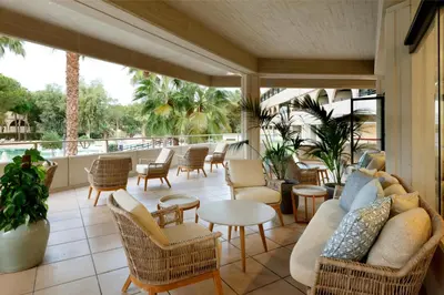 a patio with chairs and tables and a couch at Grand Palladium Sicilia Resort & Spa in Campofelice di Roccella