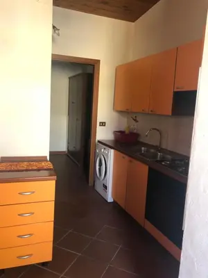 a kitchen with orange cabinets and a washer and dryer at Casetta Mondello in Mondello