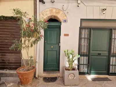 two green doors on a building with potted plants at Come a Casa by Holiday World in Palermo