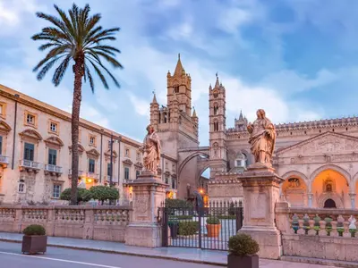 a building with a palm tree in front of it at Come a Casa by Holiday World in Palermo