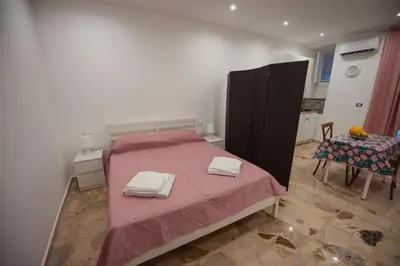a bedroom with a pink bed with two towels on it at Holiday House Annunziata 1 in Termini Imerese