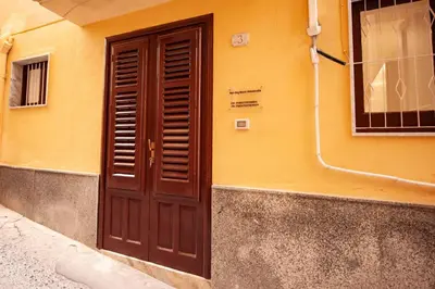 a brown door on the side of a yellow building at Holiday House Annunziata 1 in Termini Imerese