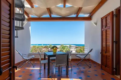 a dining room with a table and chairs and a large window at Villa Giunella in San Vito lo Capo
