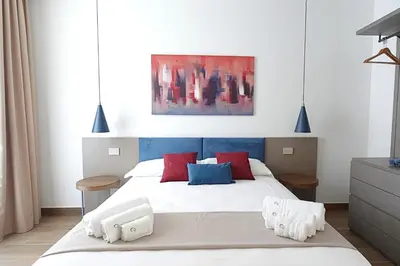 a bedroom with a white bed with red and blue pillows at Eccelso Case Vacanza in Palermo