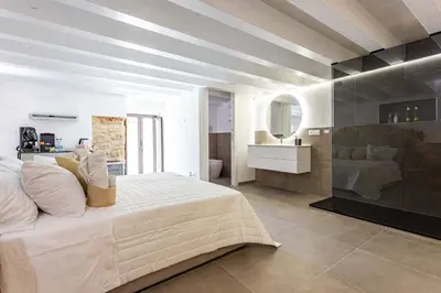 a bedroom with a large white bed and a bathroom at La Camera di Carolino in Palermo