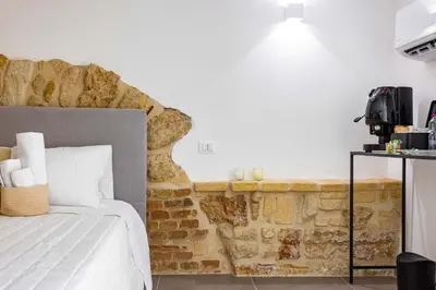 a bedroom with a bed and a stone wall at La Camera di Carolino in Palermo