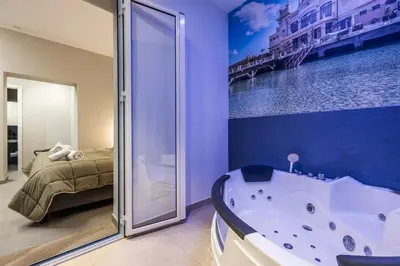 a bathroom with a bath tub and a bedroom at Lolli Boutique & SPA Mondello in Palermo