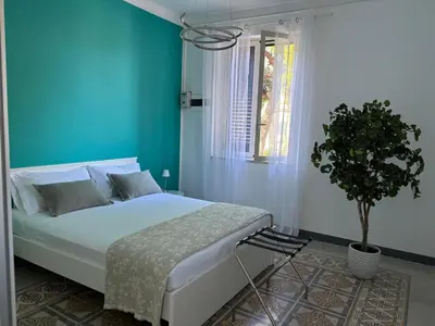 a blue bedroom with a bed and a potted plant at Le Lunette Holiday House in Palermo