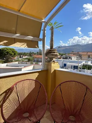 two red chairs sitting on a balcony with a palm tree at Le Lunette Holiday House in Palermo