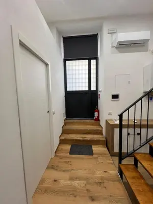 a hallway with a black door and wooden stairs at Kiccifù home in Palermo