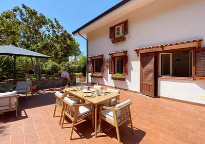 a patio with a wooden table and chairs and a house at Solemar Sicilia - Villa Alma in Palermo