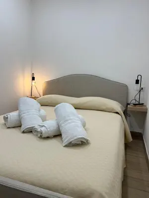a bed with towels on it with two lamps at Oasi house in Palermo