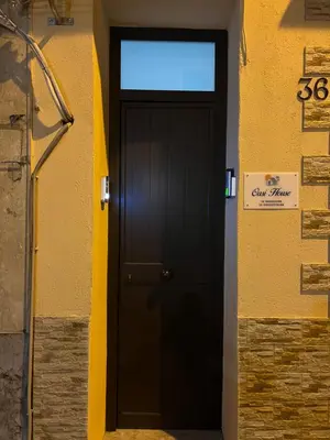 a black door in a yellow building with a sign on it at Oasi house in Palermo
