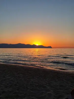 a sunset on a beach with the ocean and mountains at Dimora Anastasia - Alloggio nel cuore di Balestrate in Balestrate