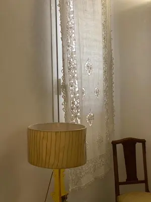 a lamp in front of a window with a curtain at PHI-Lampara in Santa Flavia