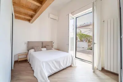 a white bedroom with a bed and a large window at Casa Clio - Mondello Home in Palermo