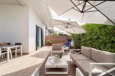 an outdoor patio with white furniture and umbrellas at Casa Clio - Mondello Home in Palermo