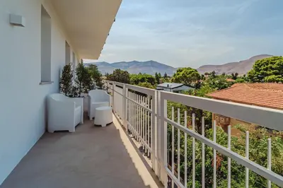 an apartment balcony with white chairs and plants at Hybrid Icon Rooms Gallery in Palermo