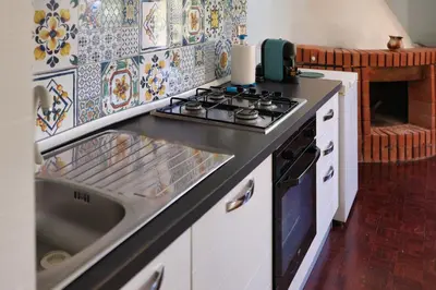 a kitchen with a stove and a sink at VFH Villa Cala del Cuore con piscina, 50 m dal mare in Santa Flavia