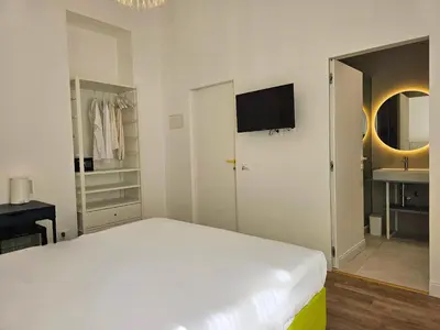 a white bedroom with a bed and a tv on the wall at Dolce Dormire in Palermo