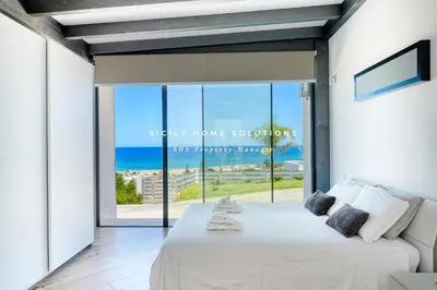 a bedroom with a bed with a view of the ocean at Appartamento in villa vista mare con jacuzzi By Sicily Home Solutions in Balestrate