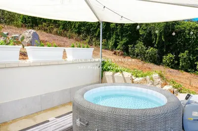 a hot tub in a backyard with an umbrella at Appartamento in villa vista mare con jacuzzi By Sicily Home Solutions in Balestrate