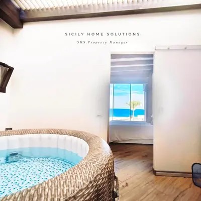 a room with a bed and a view of the ocean at Appartamento in villa vista mare con jacuzzi By Sicily Home Solutions in Balestrate