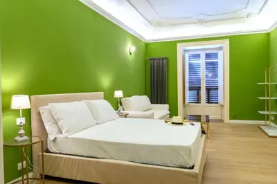 a green bedroom with a bed and a chair at 4Quarti in Palermo