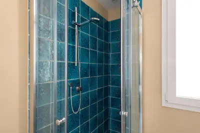 a bathroom with a shower with blue tiles at Sea Frame Design Apartments with Pool by Wonderful Italy in Santa Flavia