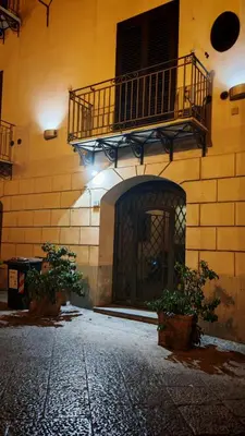a building with a balcony and a courtyard with plants at Qanat House con Terrazzo Privato in Palermo