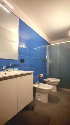 a blue bathroom with a toilet and a sink at Qanat House con Terrazzo Privato in Palermo