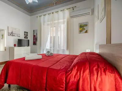 a red bed with two towels on top of it at Dimora Puccini by Holiday World in Castellammare del Golfo