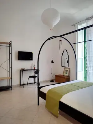 a bedroom with a large bed and a desk at Cà Mami Rooms in Palermo
