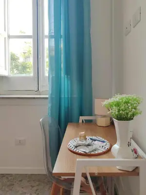 a dining room table with a blue curtain and a vase at Cà Mami Rooms in Palermo