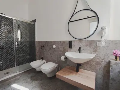 a bathroom with a sink and a toilet and a mirror at Cà Mami Rooms in Palermo