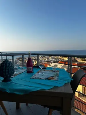 a table with a bottle of wine and glasses on a balcony at Sole Blue Apartment in Balestrate