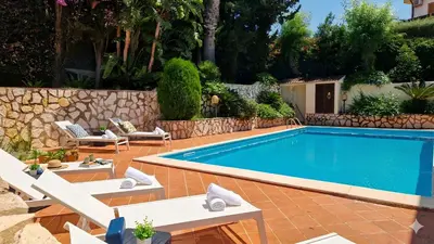 a swimming pool with two chairs and a palm tree at Villa Domus Dea Mondello in Mondello