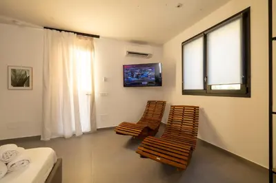 a room with two chairs and a tv on the wall at Suite le palme in Aspra