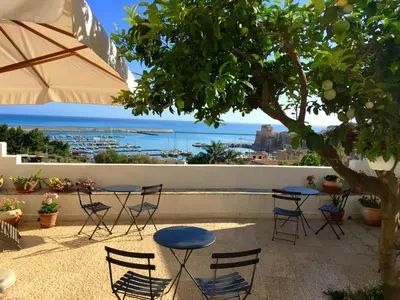 a patio with tables and chairs and a view of the ocean at Santina Suites in Castellammare del Golfo