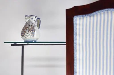 a vase sitting on a glass table next to a chair at Santina Suites in Castellammare del Golfo