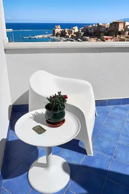a white chair with a potted plant on a table at Santina Suites in Castellammare del Golfo