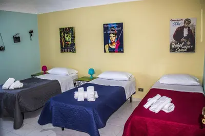 a room with three beds and posters on the wall at B&B Porta Nuova in Palermo