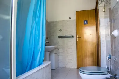 a bathroom with a blue shower curtain and a toilet at B&B Porta Nuova in Palermo