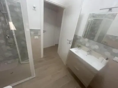 a white bathroom with a sink and a shower at Lucrezio Houses in Palermo