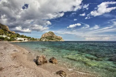 a sandy beach with rocks in the water at Appartamento La Rosa dei Venti in Porticello