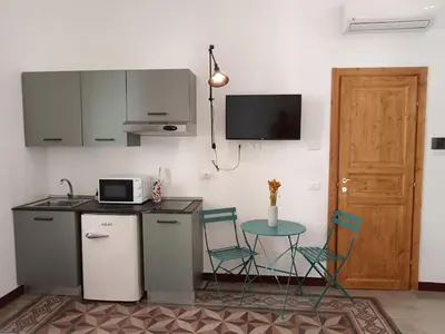 a kitchen with a table and two chairs and a microwave at Campofranco Studio in Palermo