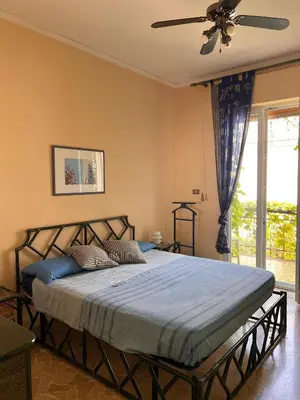 a bedroom with a bed with blue sheets and a ceiling fan at La terrazza sul mare in Palermo