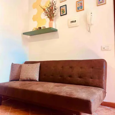 a brown leather couch in a room with a wall at Casamori 2- nel cuore di Palermo, mercato Ballarò in Palermo